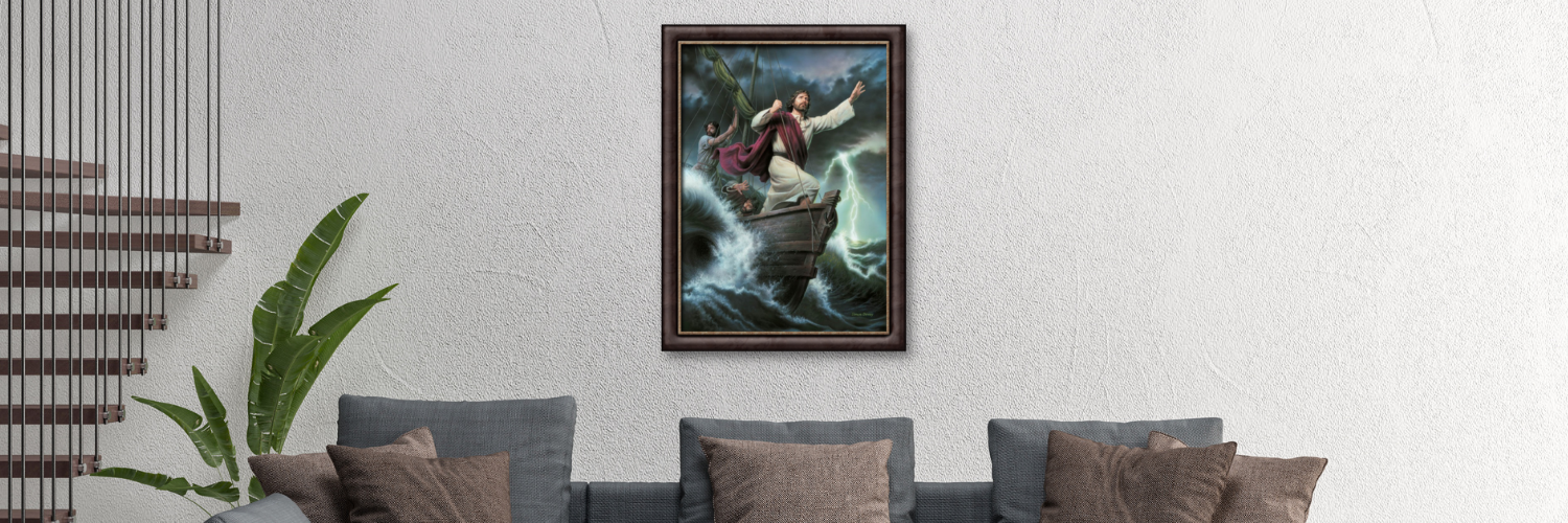 A modern living room with a gray sectional sofa, brown and gray pillows, a large framed painting of a figure on a boat in stormy seas, and a green plant near a staircase with vertical railings.