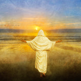Jesus Christ with his arms spread wide towards the sunset on the beach.